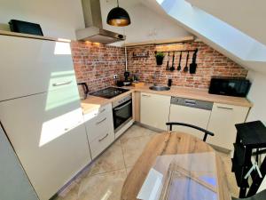 a kitchen with white cabinets and a brick wall at Studio apartman Varadero in Bjelovar
