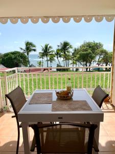 una mesa y sillas en un patio con vistas al océano en Le Cocon Créole studio vue mer Village Vacances, en Sainte-Anne