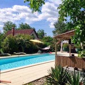 a swimming pool with a pergola next to a house at Dordogne Farmhouse in Beaulieu-sur-Dordogne