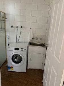 een kleine badkamer met een wasmachine en een wastafel bij Harbour View 49 Urch Street Unit 2 in Geraldton