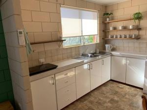 een keuken met witte kasten, een wastafel en een raam bij Harbour View 49 Urch Street Unit 2 in Geraldton