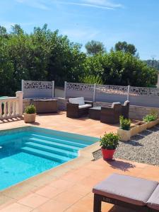 a swimming pool with chairs and a table next to it at Cosy rez-de-jardin de villa in Brignoles