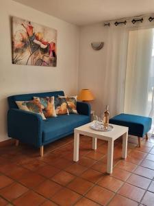 ein Wohnzimmer mit einem blauen Sofa und einem Tisch in der Unterkunft Cosy rez-de-jardin de villa in Brignoles
