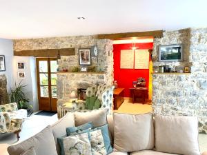 - un salon avec un canapé et un mur en pierre dans l'établissement Dordogne Farmhouse, à Beaulieu-sur-Dordogne