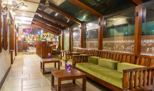 a restaurant with a green couch and tables in a room at Treebo Trend Bhairavee in Pune