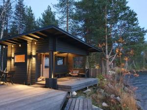 a cabin on the water with a wooden deck at Scandinavian lakeside cottage in Rovaniemi