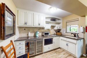 cocina con armarios blancos, fregadero y microondas en Robinhood Casita en Grass Valley