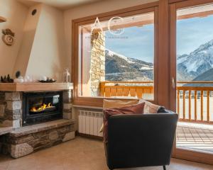 a living room with a fireplace and a chair at Villa Nice View in Ponte di Legno