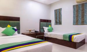 a bedroom with two beds and two windows at Treebo Bhairavee, Baner in Pune +27 photos