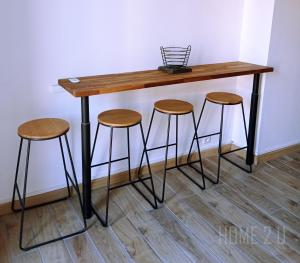 une table en bois avec tabourets à côté d'un mur dans l'établissement Echappée Belle à Montauban - parking - centre ville, à Montauban 4 autres photos