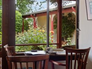 una mesa y sillas en un porche con ventana en The Noble Grape Guesthouse, en Cowaramup