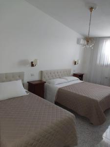 Habitación de hotel con 2 camas y lámpara de araña. en rooms speedy vicino aeroporto e fiera di roma, en Fiumicino