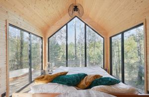 a bedroom with a bed in a room with windows at Forestic Lietuva in Vilionys