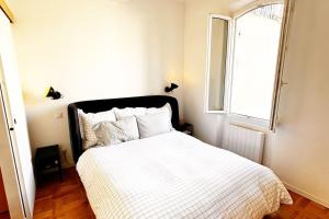 um quarto com uma cama com um edredão branco e uma janela em Magnifique Nid douillet au Cœur Marseille Reformés em Marselha