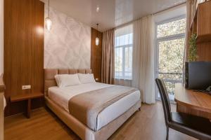 een slaapkamer met een bed, een bureau en een televisie bij Park Hotel Tskaltubo - Balneo Resort in Tskaltubo