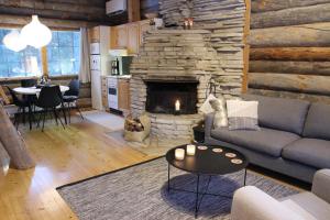 uma sala de estar com um sofá e uma lareira de pedra em Lapland Cabin Vonkamies em Luosto