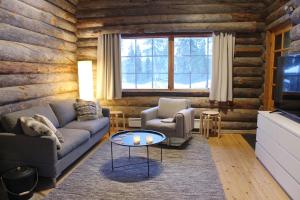 a living room with a couch and two chairs and a table at Lapland Cabin Vonkamies in Luosto