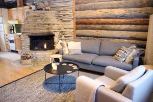 a living room with a couch and a stone fireplace at Lapland Cabin Vonkamies in Luosto