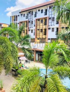 a hotel with palm trees in front of a building at La Carmela de Boracay Hotel in Boracay