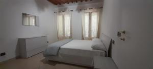 a white bedroom with a bed and two windows at Appartamento Il Pozzo in Capannori