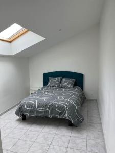 een slaapkamer met een bed met een zwart en grijs dekbed bij Gîte à la campagne - 8 personnes in Argentré