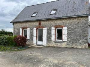 een oud stenen huis met witte deuren en ramen bij Gîte à la campagne - 8 personnes in Argentré