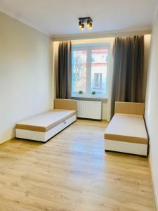 two beds in a room with two windows at Gold Apartament in Świdnik