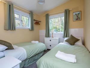 2 camas en una habitación con 2 ventanas en Bridgend Chalet on Reelig Estate Near Inverness, en Kirkhill
