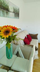 Apartamento Fuente del Genil. في Fuente Vaqueros: مزهرية من الزهور تجلس على طاولة بجوار أريكة