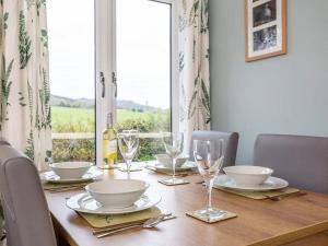 uma mesa de madeira com pratos e copos de vinho em Bridgend Chalet on Reelig Estate Near Inverness em Kirkhill