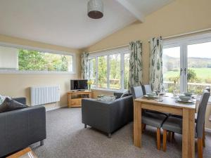 sala de estar con mesa, sillas y ventanas en Bridgend Chalet on Reelig Estate Near Inverness, en Kirkhill