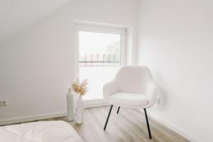 Una silla blanca en una habitación blanca con ventana en Küsten Suite de See - Suite 4 seitliche Deichlage, Balkon, 89qm, en Greetsiel