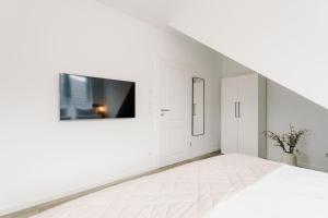 Habitación blanca con TV en la pared en Küsten Suite de See - Suite 4 seitliche Deichlage, Balkon, 89qm, en Greetsiel