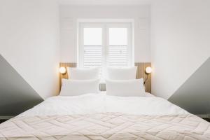 a white bedroom with two beds and two windows at Küsten Suite de See - Suite 4 seitliche Deichlage, Balkon, 89qm in Greetsiel