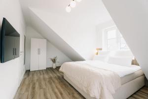 a white bedroom with a white bed and wooden floors at Küsten Suite de See - Suite 4 seitliche Deichlage, Balkon, 89qm in Greetsiel