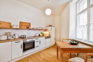 a kitchen with white cabinets and a wooden table at Villa am Mägdebrunnen in Stralsund