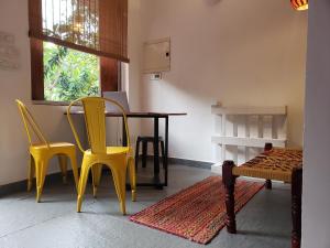 a room with yellow chairs and a table and a window at Adi Shakti Guesthouse in Querim