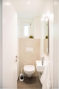 La salle de bains blanche est pourvue de toilettes et d'un lavabo. dans l'établissement Ferienhaus mit Garten Tgease Schilendra-Lantsch-Lenz-Lenzerheide, à Lenz