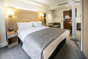 um quarto de hotel com uma cama grande e uma casa de banho em Holiday Inn London Kensington High St., an IHG Hotel em Londres