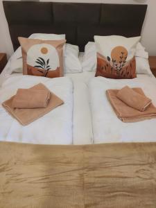 2 camas con sábanas blancas y almohadas en Fészek Fogadó - Pension Nest, en Mosonmagyaróvár