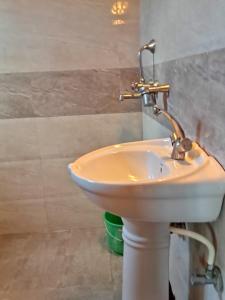 La salle de bains est pourvue d'un lavabo blanc. dans l'établissement Hotel Holidays Inn - Bagpacker's Home, à Sauraha