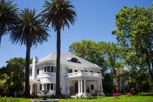 a white house with two palm trees in the yard at Palm House Boutique Hotel in Cape Town