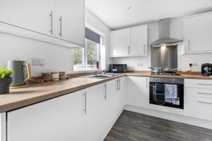 cocina blanca con armarios blancos y fogones en Comfortable 2 Bedroom Home with Secure Parking, en Nottingham
