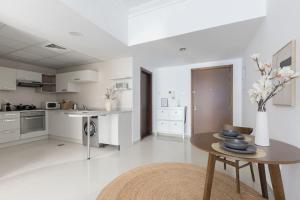 a white kitchen with a table and a vase of flowers at COLIFE 21 floor, 7 min drive from Dubai Mall 136 in Dubai