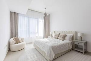 a white bedroom with a white bed and a chair at COLIFE 21 floor, 7 min drive from Dubai Mall 136 in Dubai