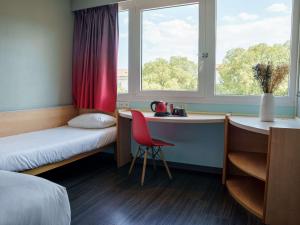 Zimmer mit einem Bett, einem Schreibtisch und einem Fenster in der Unterkunft Ibis Alès Centre Ville in Alès