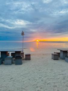 a picnic table on the beach with a sunset at Cozy Khanom โคซี่ ขนอม in Ban Na Dan