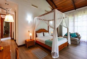 1 dormitorio con cama con dosel y sofá en Anse Lazio Lodge en Anse Lazio