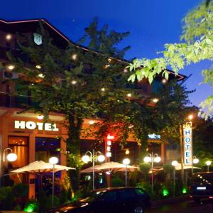 un hôtel la nuit avec des voitures garées devant lui dans l'établissement Hotel Berito, à Momtchilgrad