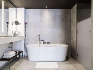 uma banheira branca na casa de banho com um lavatório em Molitor Hôtel & Spa Paris - MGallery Collection em Paris
